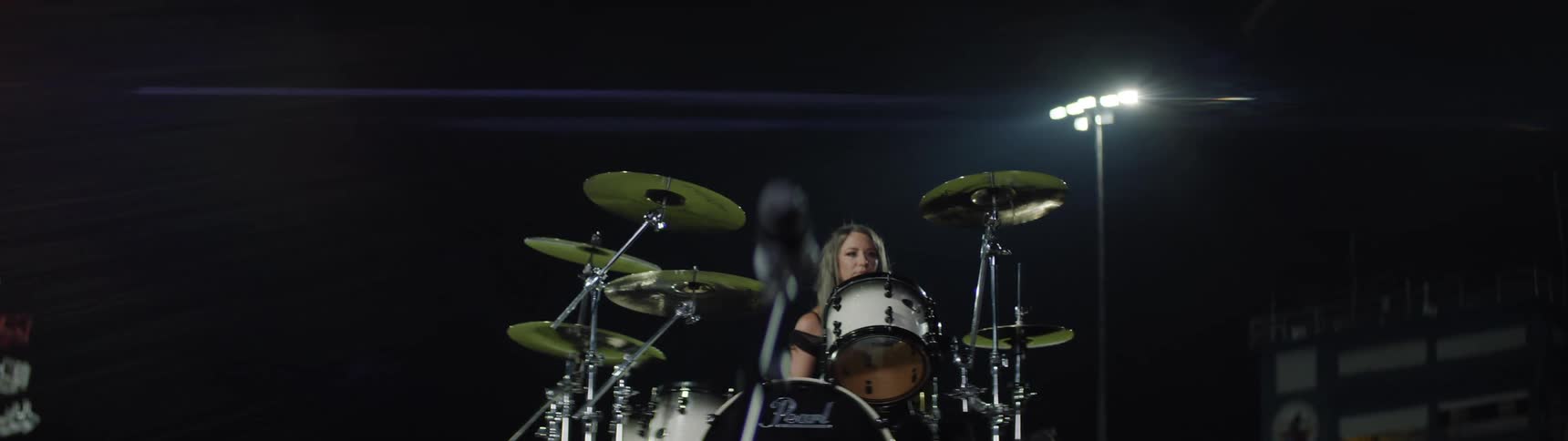 The woman sits down at her drums outside at night