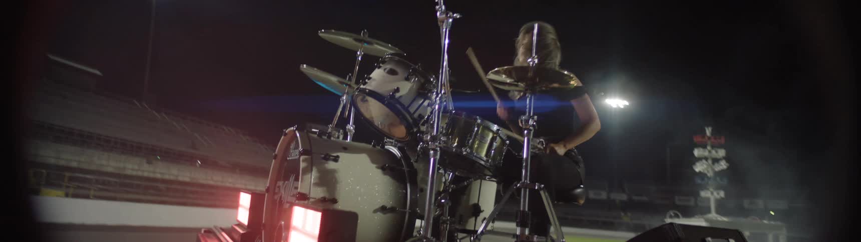 Drummer performing on stage surrounded by smoke and stage lights