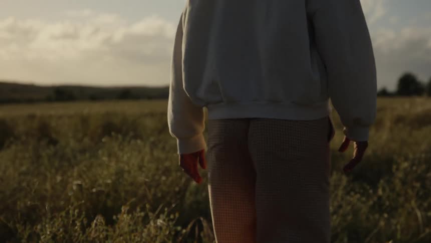 The woman is walking through the tall grass