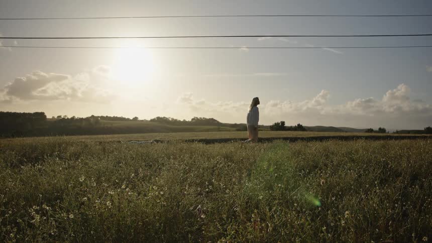Woman walking through an open field under the afternoon sun