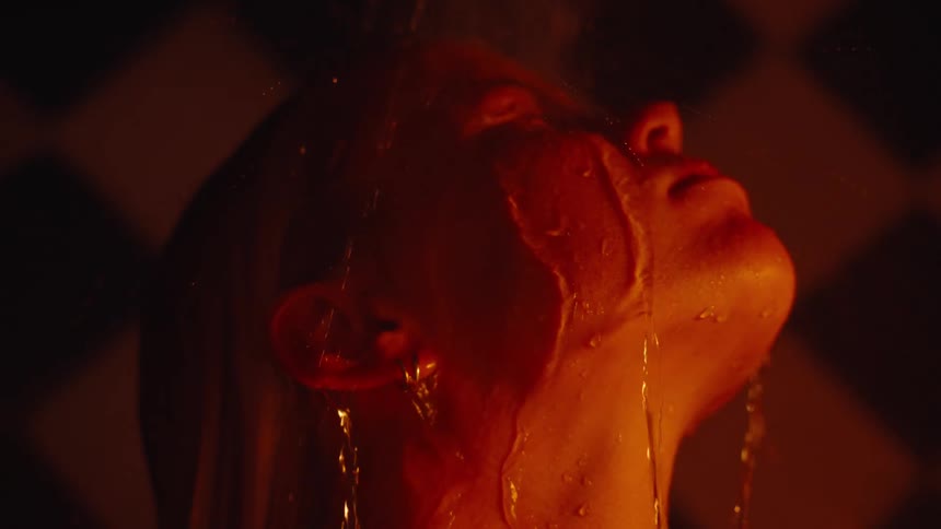 Person letting water flow down their face under orange lighting