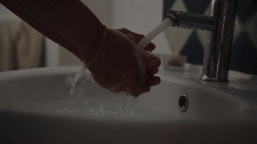 A person is washing hands at a sink water is flowing steady and the person is using it to wash hands