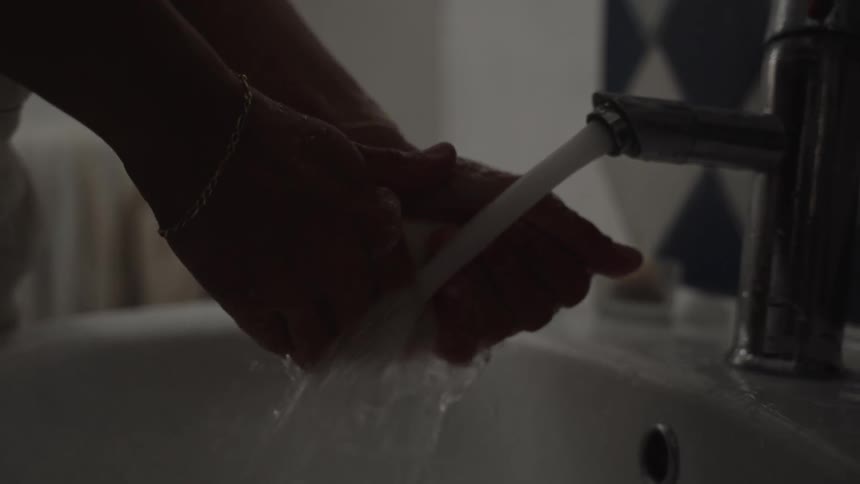 A person washes their hands at the faucet in the bathroom