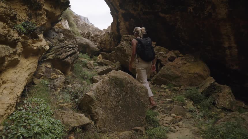 Woman walking among rocky formations with a backpack on her back