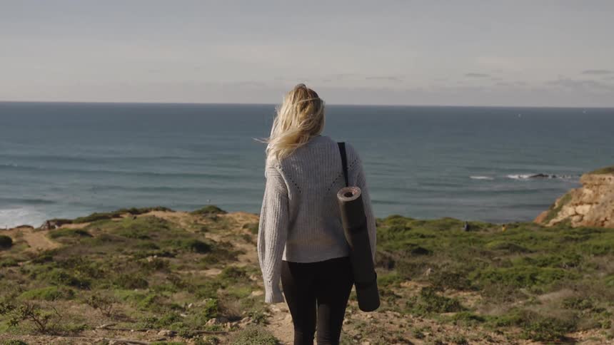 A woman and her dog walk along the coast