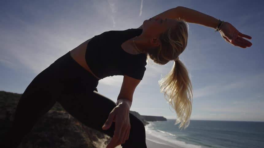 Woman stretching by the seaside under a sunny sky