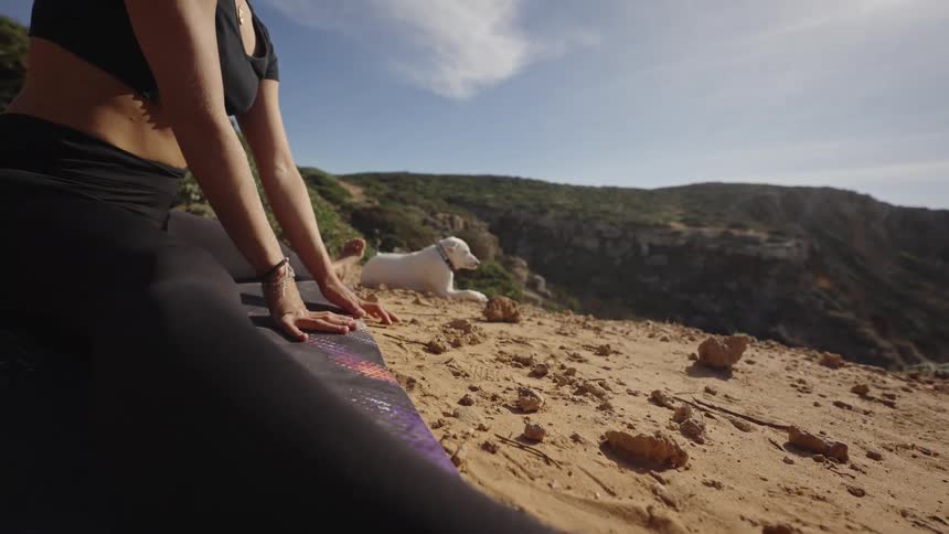Woman stretching on a mat in a mountainous area under the morning sun