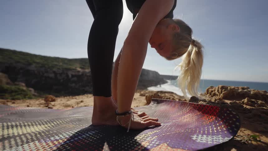 Woman practices yoga on a cliff near the ocean beach