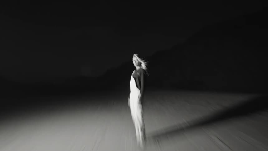 Woman walking alone at night in a deserted blackandwhite landscape