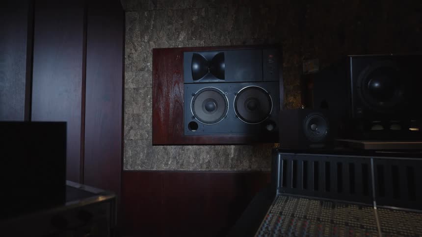 Recording studio speakers and sound console in dim lighting