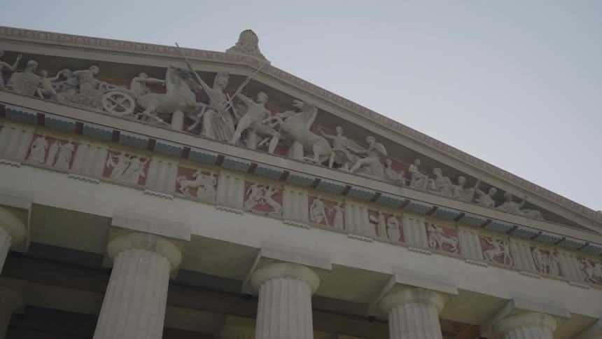 Triangular pediment displays sculptural relief with human and horse figures in a mythological scene
