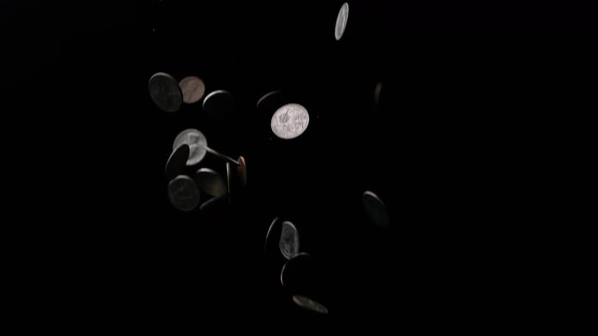 Coins are falling from above against a black background