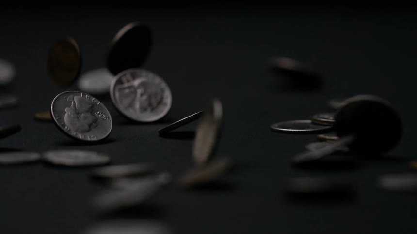 Metal coins falling and bouncing on a dark surface