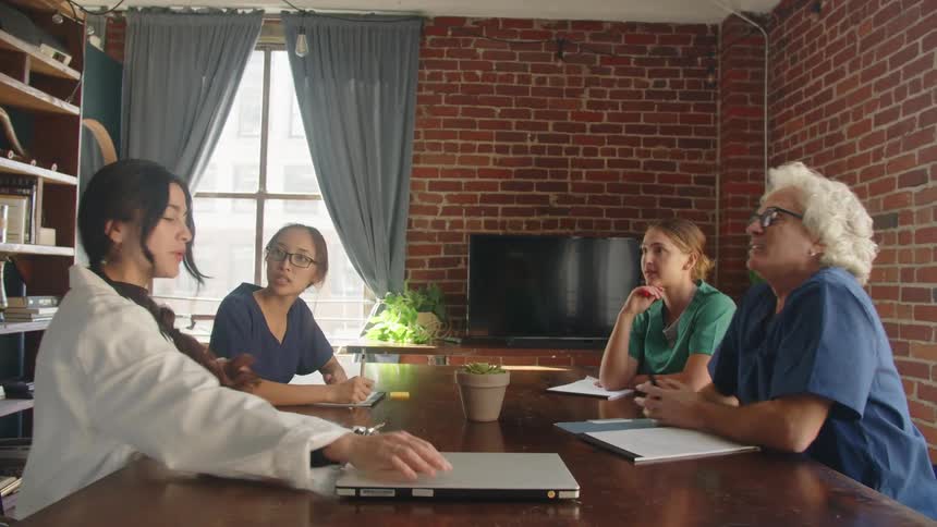 Healthcare professionals gathered in discussion around a table with a laptop