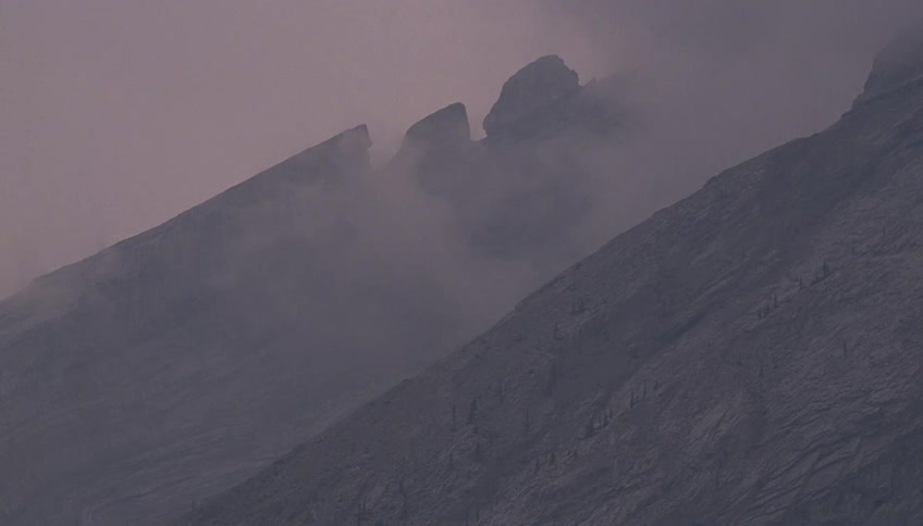 Dense fog covers a rocky mountain slope on a foggy day