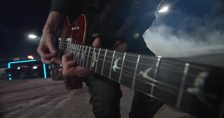 Musician playing electric guitar under stage lights and smoke