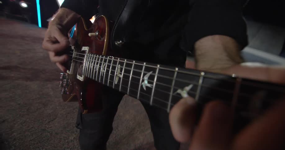 Musician playing an electric guitar outdoors at night