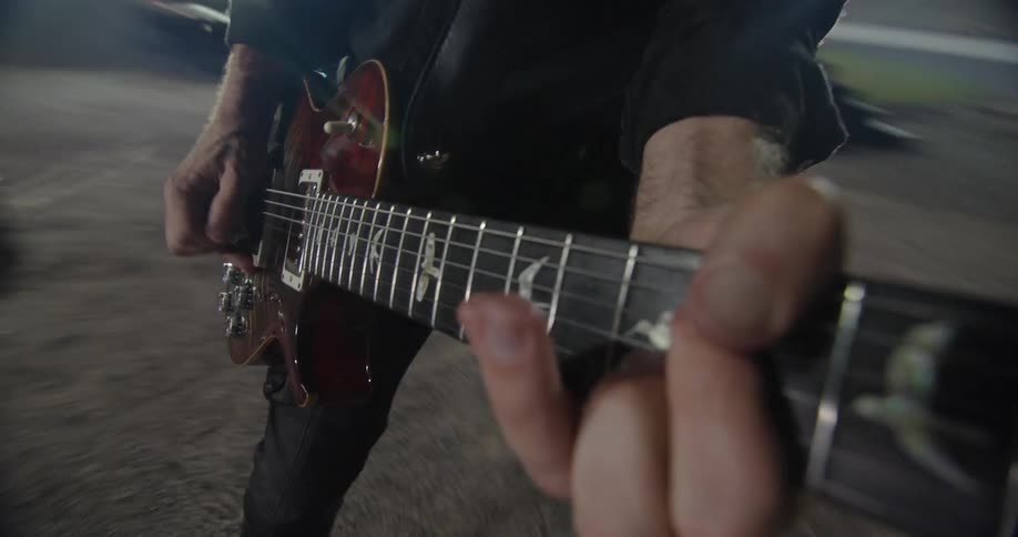 A mans hands playing a guitar at a concert