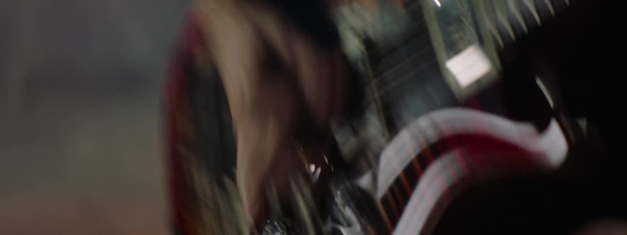 A man performs on stage with a red guitar dancing as he plays during a concert show