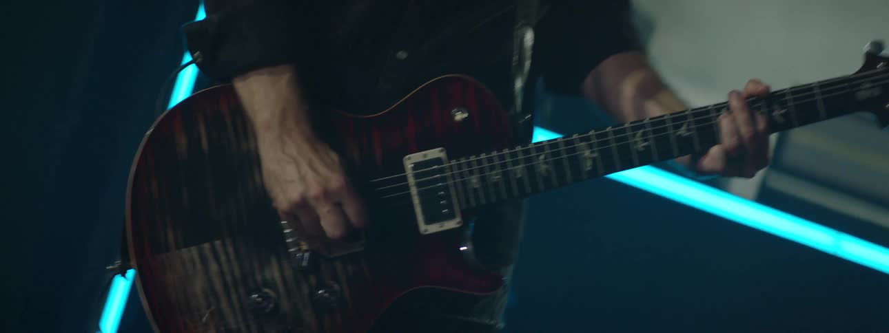 A man playing a prs electric guitar with bird inlays and a flame maple red burst top