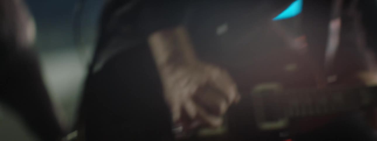 Hand strumming a guitar in a softly lit and blurred setting