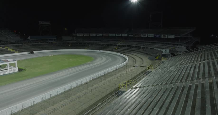 Empty stands and illuminated track of a stadium at night