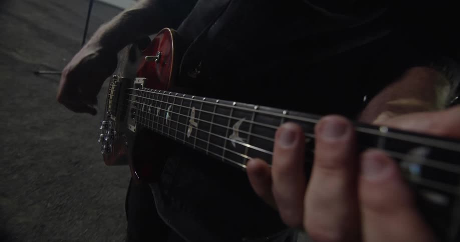 The video is an extreme closeup shot of a hand with a subtle tattoo gently touching the rough textured surface of tree bark the lighting highlights the warm reddishbrown and dark tones of the bark