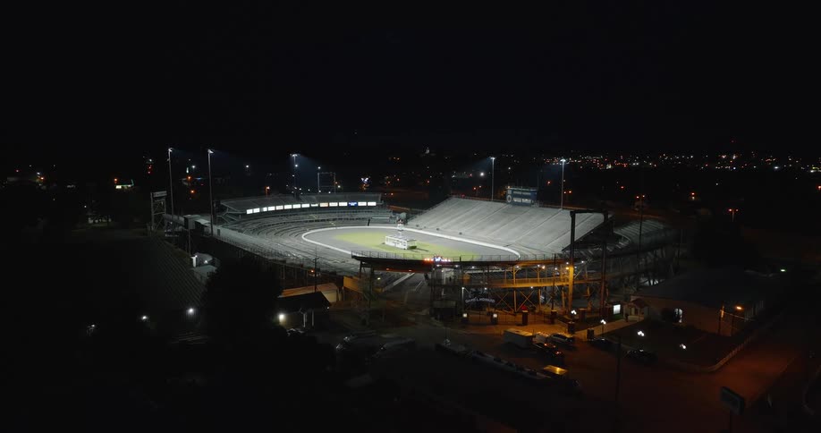 Sports field lights illuminate a stadium located near the city at night