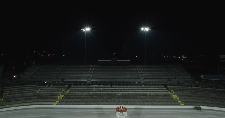 Empty racetrack with illuminated stands under the night sky