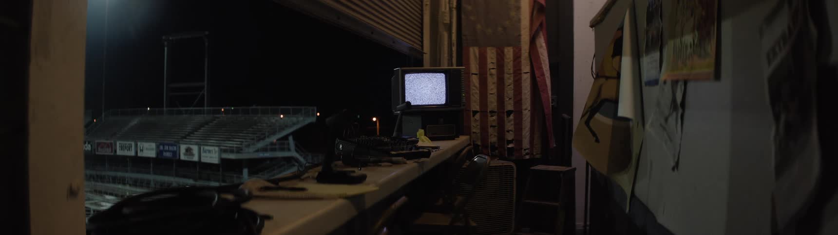 Control booth with staticfilled monitor overlooking empty stands at night
