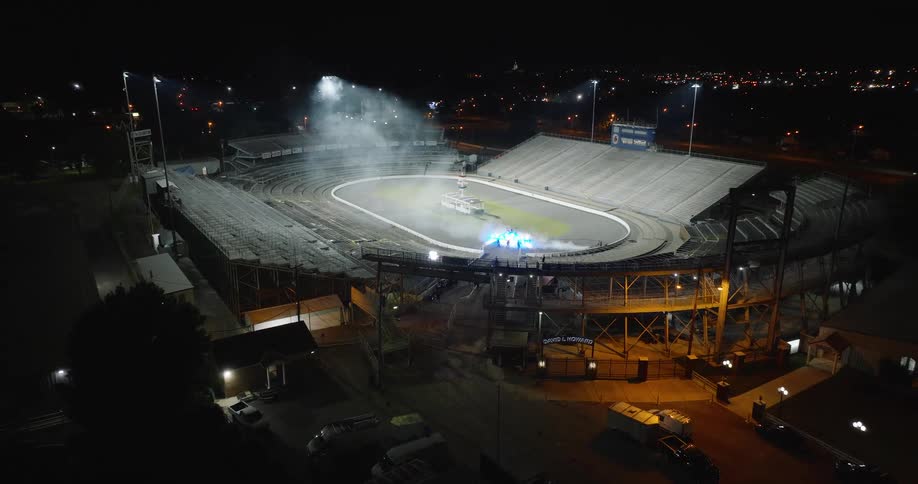 Stadium lit at night with smoke in the center of the track