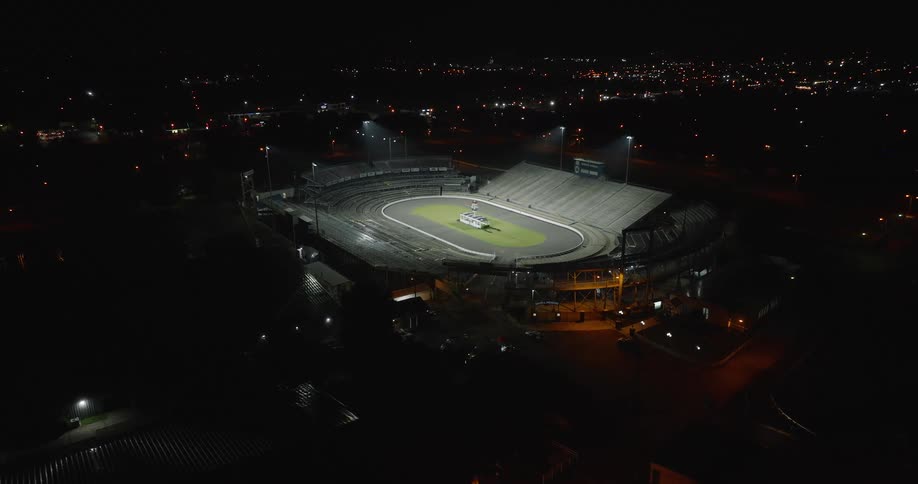 Aerial view of a stadium lit up at night in an urban area
