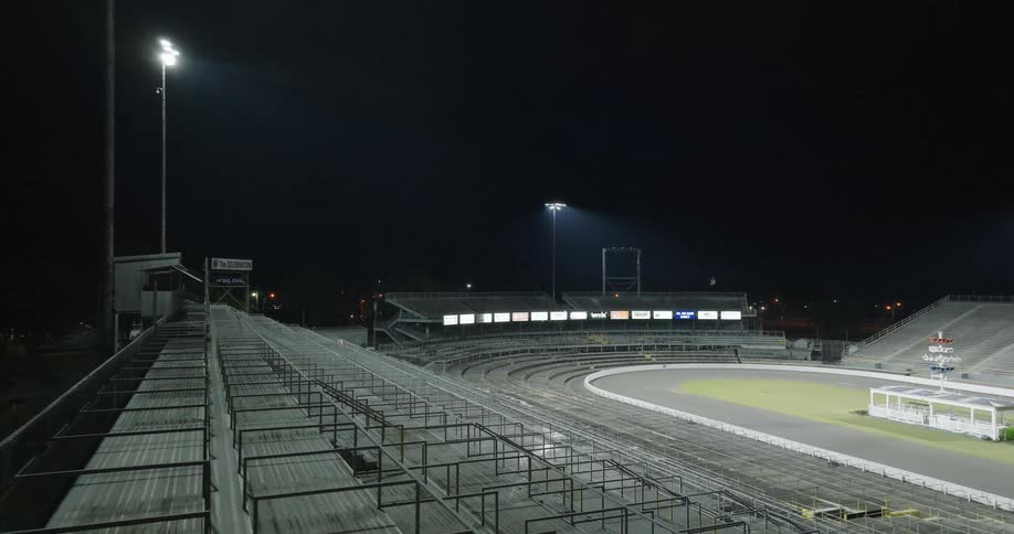 The lamp posts light up the sports stadium at night