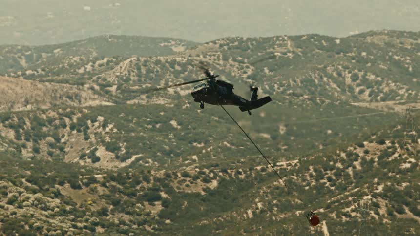 Aerial of a helicopter flying with suspended supplies in the air during daytime