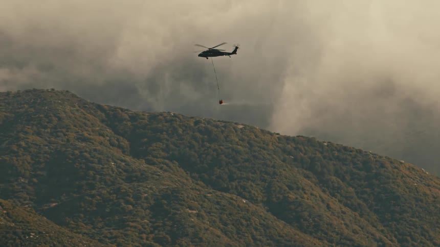 Helicopter flying over a mountain carrying equipment