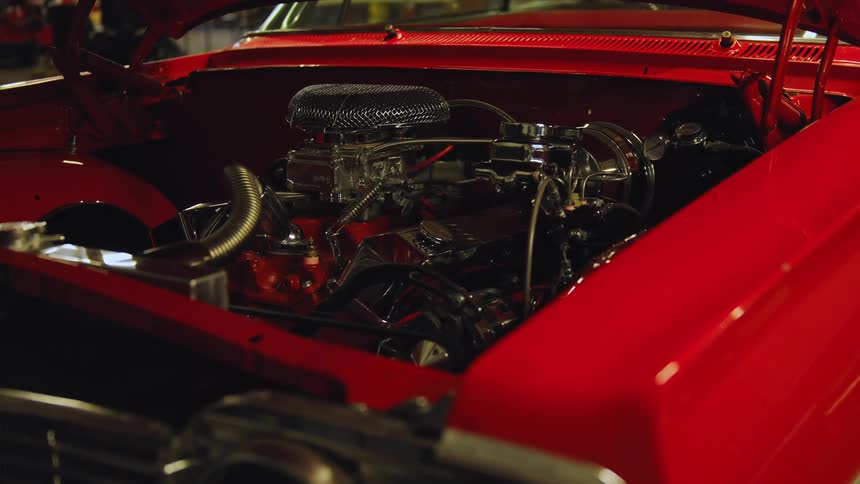 Chrome engine exposed in the bay of a classic red car
