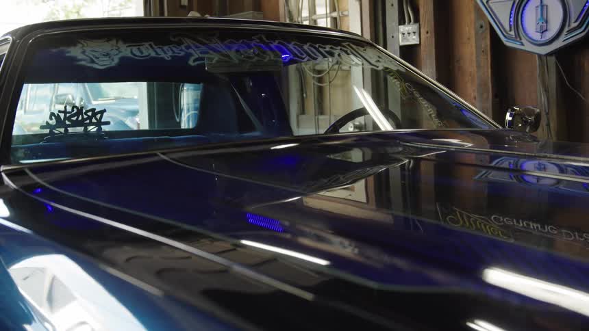Blue classic car parked inside a garage with custom decals