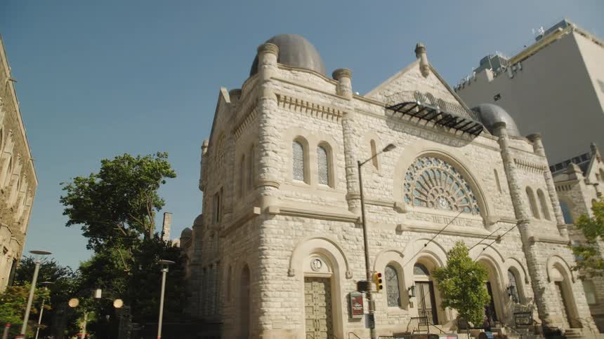 Historic stone building with domes and stained glass on a sunny urban corner