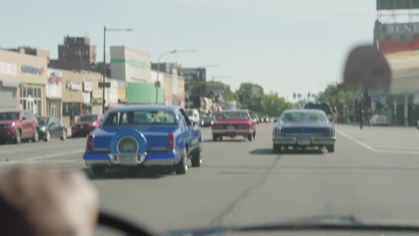 Cars move along a busy city road at midday filling the street with steady traffic