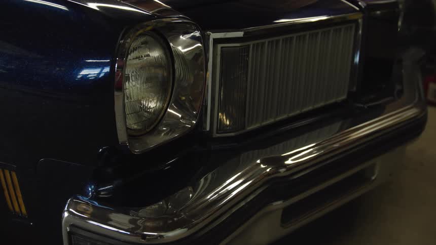 Headlight and chrome grille of a classic car in focus