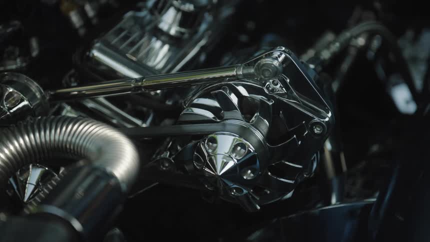A shining steel car engine is exposed beneath the raised hood at midday