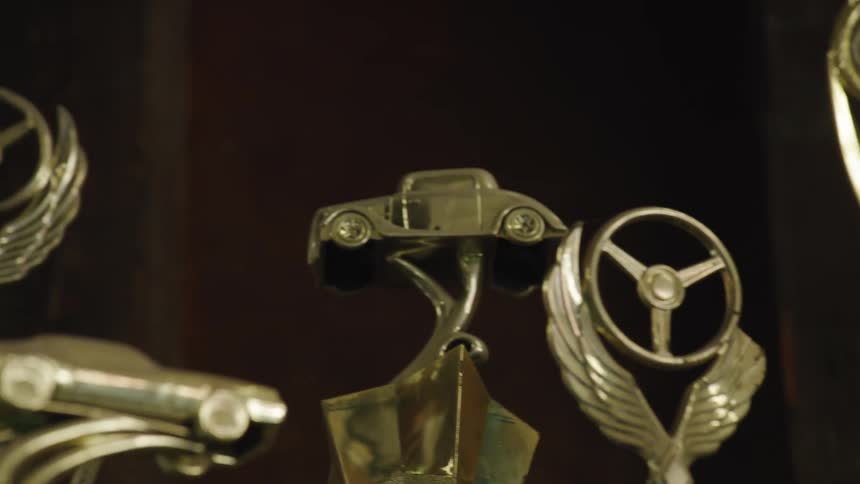 Multiple motorsport trophies stand together in the same area