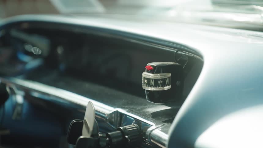 Orientation device mounted on metallic dashboard in vintage car with directional dial