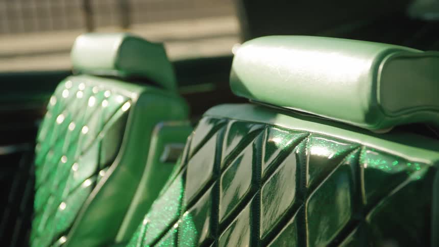 A closeup of glossy green quilted car seats with matching headrests in sunlight