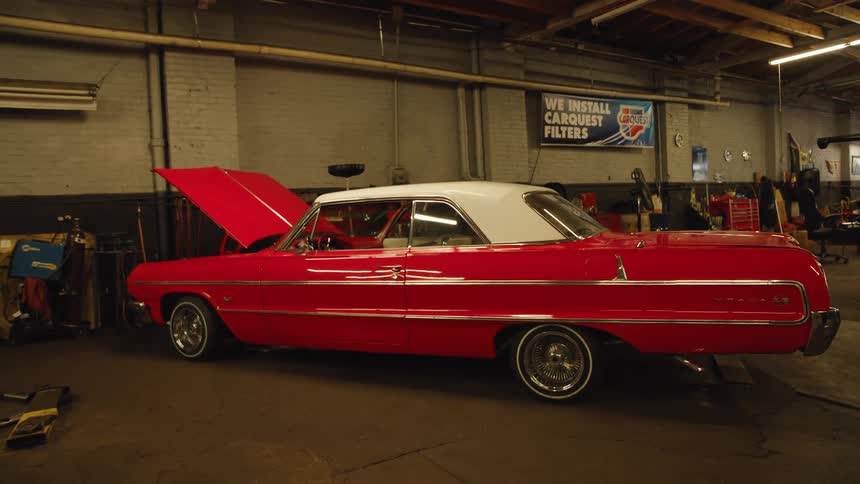 Red classic car with its hood open in a mechanic workshop