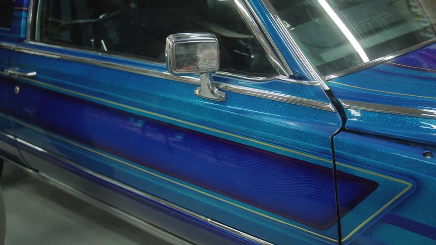 Close up of the side of a blue vintage vehicle parked in a garage