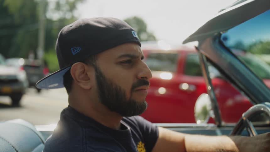 Close up of a young man driving a vintage car on a city street during daytime