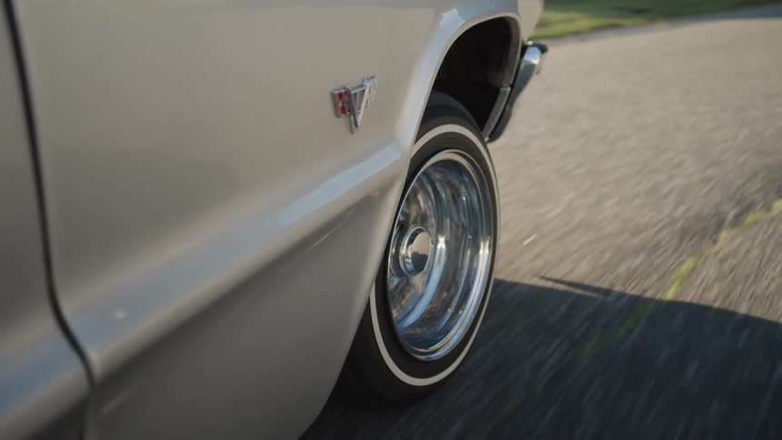Chrome wheel of a classic car in motion along the road