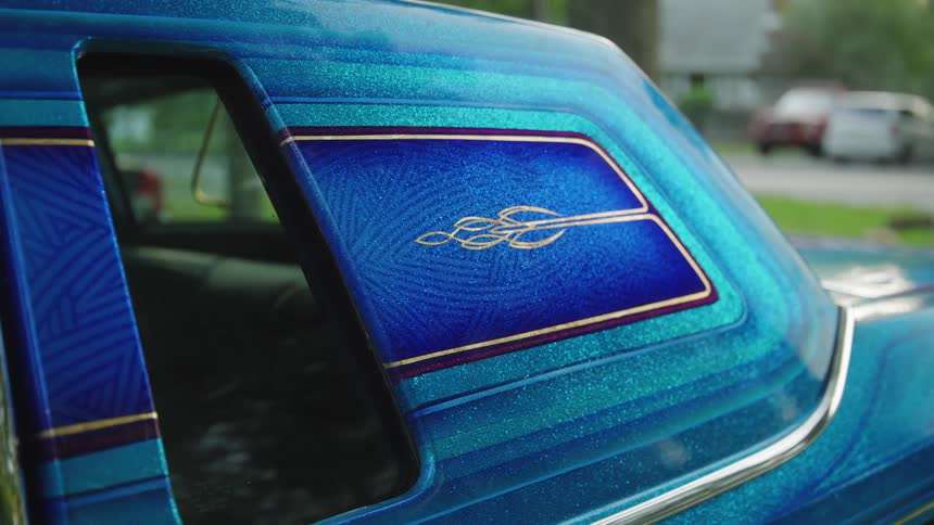 Side detail of a metallic blue car with gold pinstripe flames design