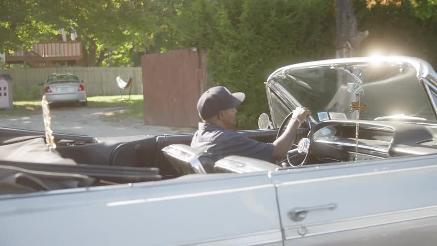 Man driving a vintage convertible under sunlight